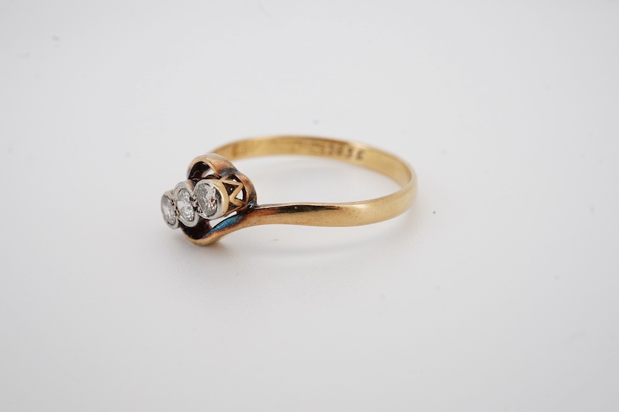 An 18ct, plat. and three stone diamond set crossover ring, size P, gross weight 2.1 grams. Condition - fair